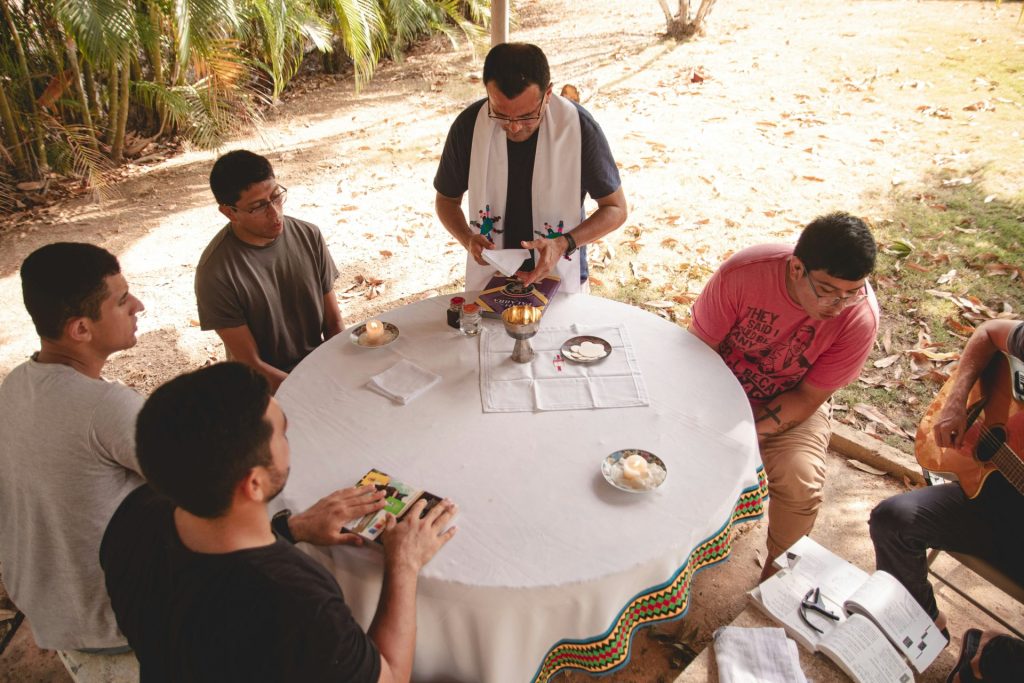 People gather around a table, perhaps a religious ceremony.